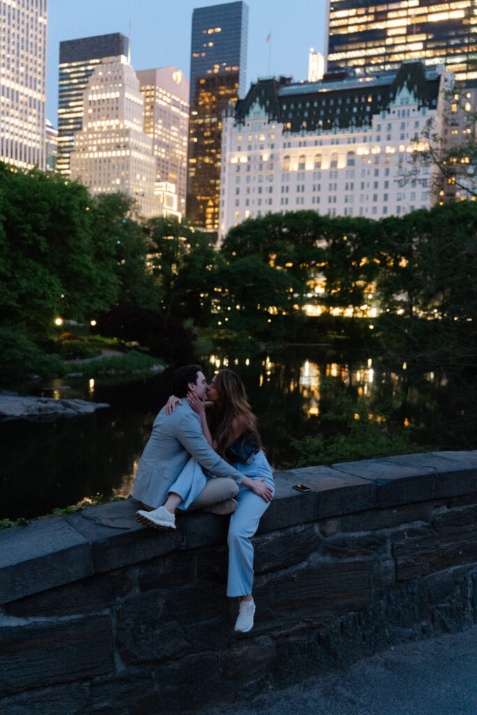 Romantic couple kissing in Central Park at night with the New York City skyline in the background