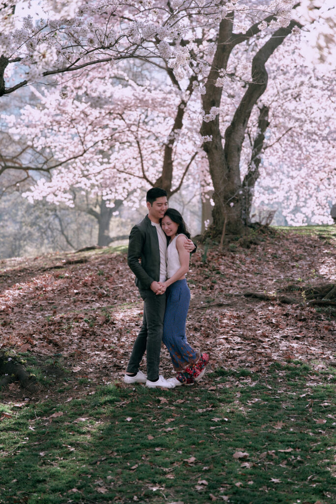 Couple embracing under cherry blossom trees in Central Park, New York City